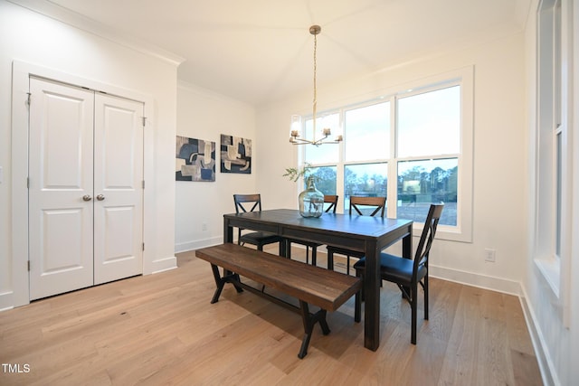 dining space with ornamental molding, light hardwood / wood-style floors, and an inviting chandelier