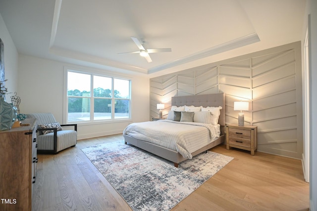 bedroom featuring a tray ceiling, ceiling fan, and light hardwood / wood-style floors