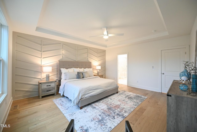 bedroom with a tray ceiling, ceiling fan, and light hardwood / wood-style floors