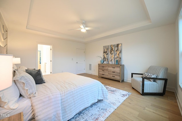 bedroom featuring a raised ceiling, ceiling fan, and light hardwood / wood-style flooring