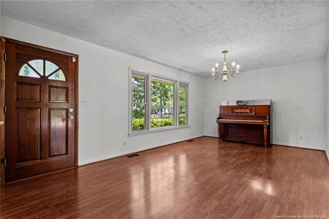 entryway with dark hardwood / wood-style flooring, a notable chandelier, and a textured ceiling