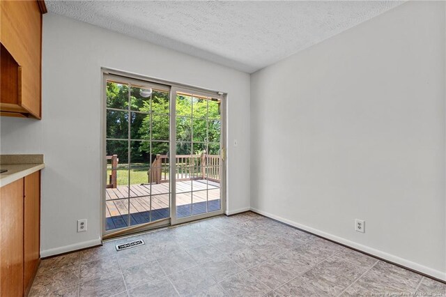 tiled empty room featuring a textured ceiling