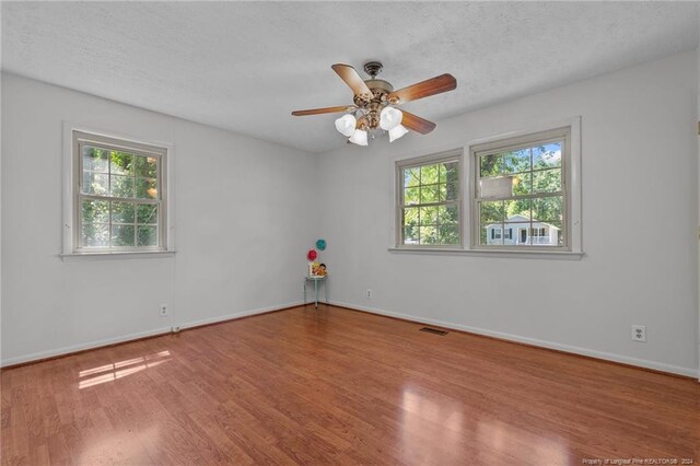 unfurnished room featuring hardwood / wood-style flooring, ceiling fan, and a textured ceiling