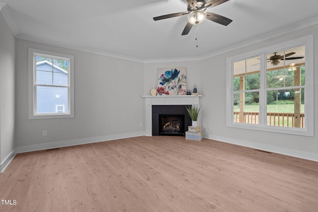 unfurnished living room featuring ornamental molding, ceiling fan, light hardwood / wood-style flooring, and plenty of natural light