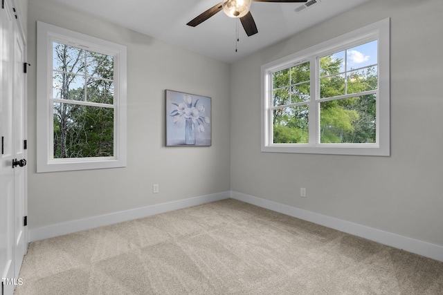 carpeted empty room with ceiling fan and a wealth of natural light