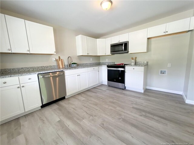 kitchen with light hardwood / wood-style floors, appliances with stainless steel finishes, white cabinetry, and light stone counters