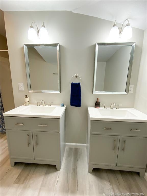 bathroom featuring wood-type flooring, large vanity, and dual sinks