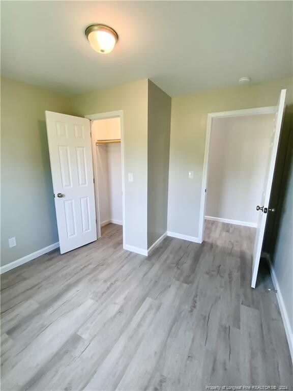 unfurnished bedroom featuring wood-type flooring and a closet