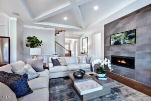 living room with a tiled fireplace, wood-type flooring, and coffered ceiling