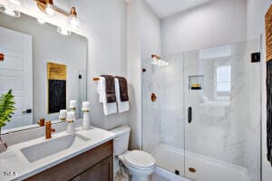 bathroom with toilet, an enclosed shower, and vanity