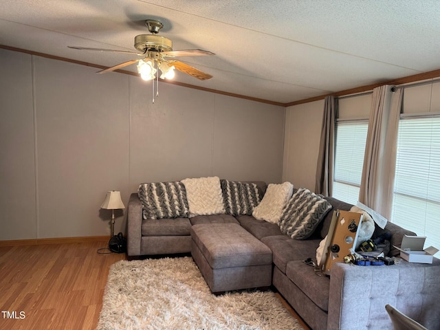 living room featuring a textured ceiling, ceiling fan, light wood-type flooring, and ornamental molding