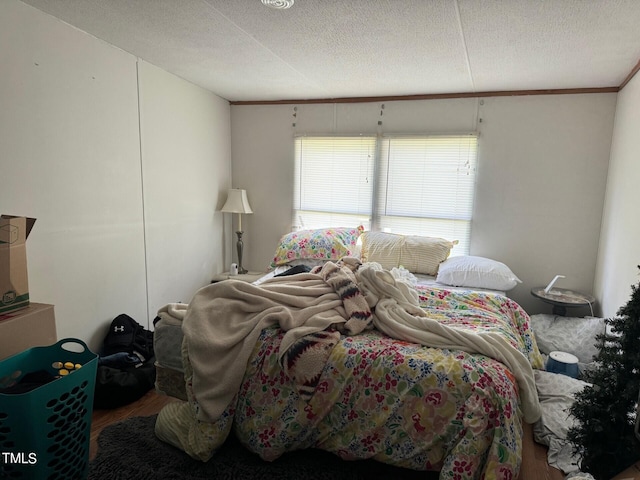 bedroom featuring crown molding, hardwood / wood-style flooring, and a textured ceiling