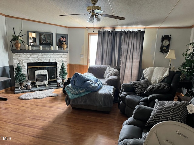 living room featuring ceiling fan, crown molding, a textured ceiling, hardwood / wood-style flooring, and a fireplace