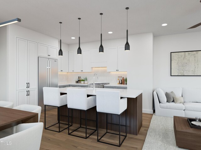 kitchen with open floor plan, light countertops, light wood finished floors, and stainless steel built in refrigerator