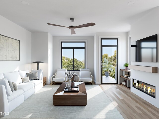 living area featuring a ceiling fan, a glass covered fireplace, baseboards, and wood finished floors