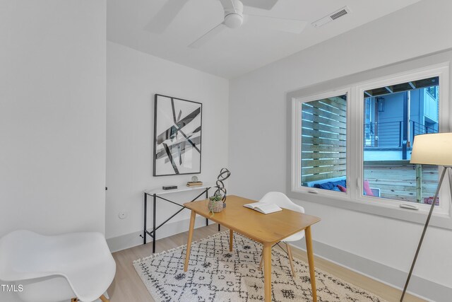 office space featuring baseboards, visible vents, ceiling fan, and light wood finished floors