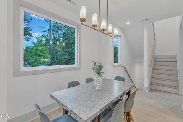 dining area featuring light wood-type flooring, a healthy amount of sunlight, and visible vents