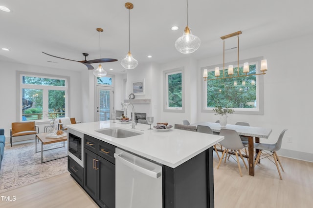 kitchen featuring light countertops, a sink, built in microwave, dark cabinetry, and dishwasher