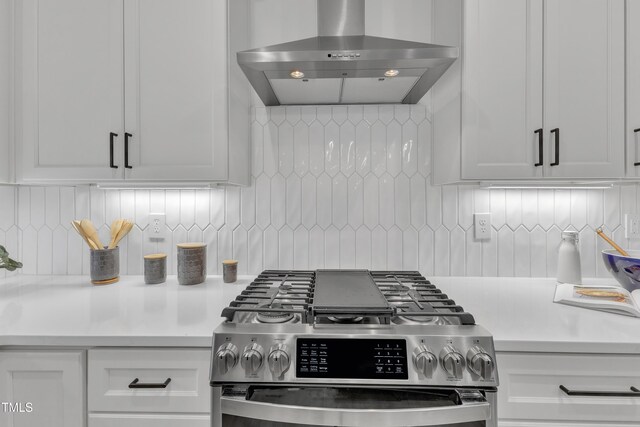 kitchen featuring wall chimney exhaust hood, light countertops, backsplash, and gas stove