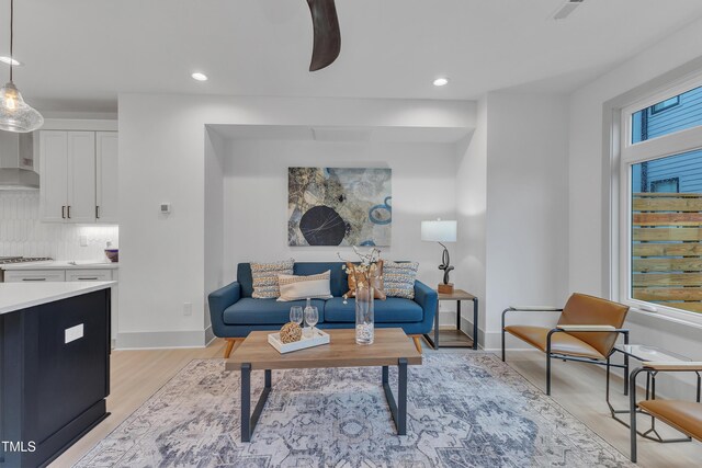 living area featuring recessed lighting, baseboards, and light wood finished floors