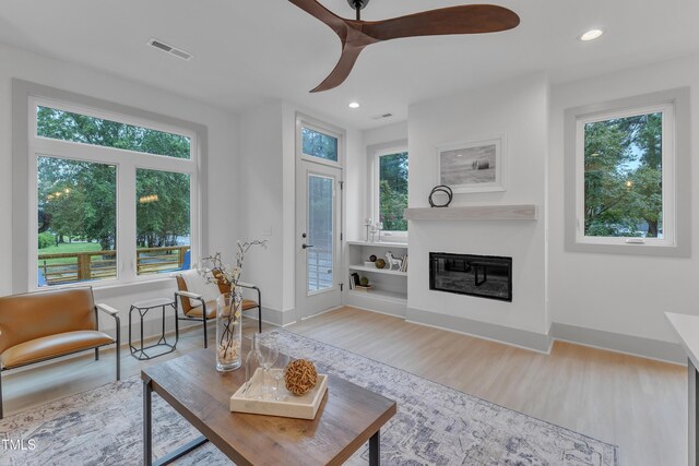 living area featuring recessed lighting, visible vents, wood finished floors, and a glass covered fireplace