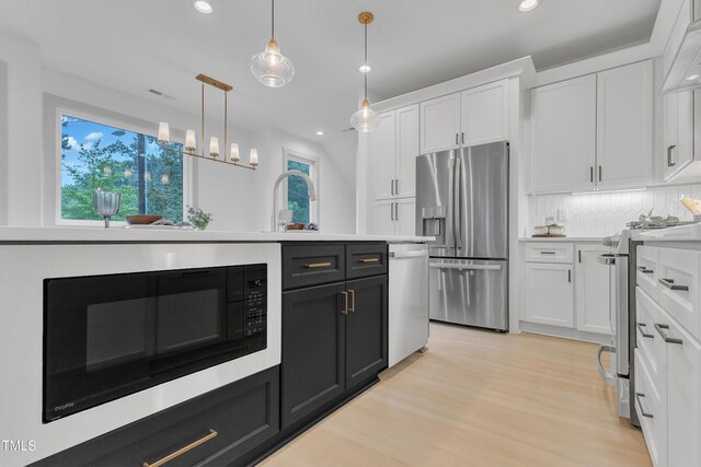 kitchen with appliances with stainless steel finishes, light countertops, white cabinetry, and backsplash