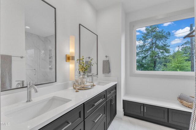 bathroom with marble finish floor, a sink, a marble finish shower, and double vanity