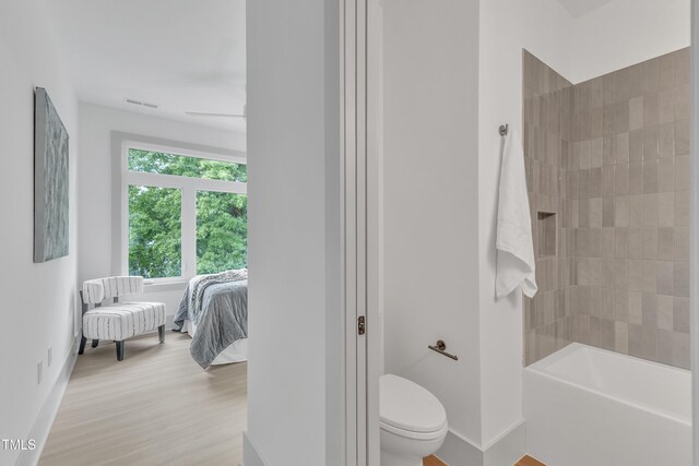 ensuite bathroom featuring connected bathroom, toilet, wood finished floors, visible vents, and baseboards