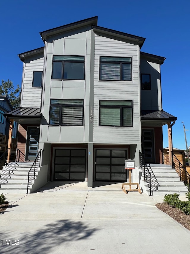 contemporary house with metal roof, driveway, a standing seam roof, and a garage