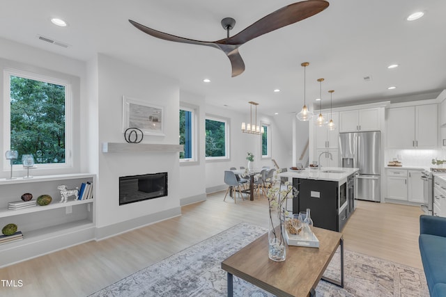 living room featuring ceiling fan, sink, and light wood-type flooring