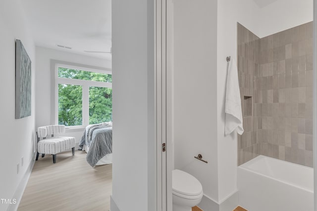 ensuite bathroom with visible vents, toilet, ensuite bath, wood finished floors, and baseboards