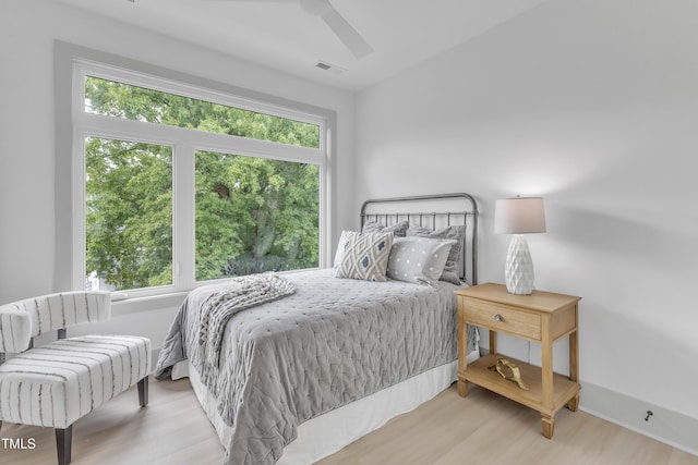 bedroom featuring a ceiling fan, visible vents, and wood finished floors