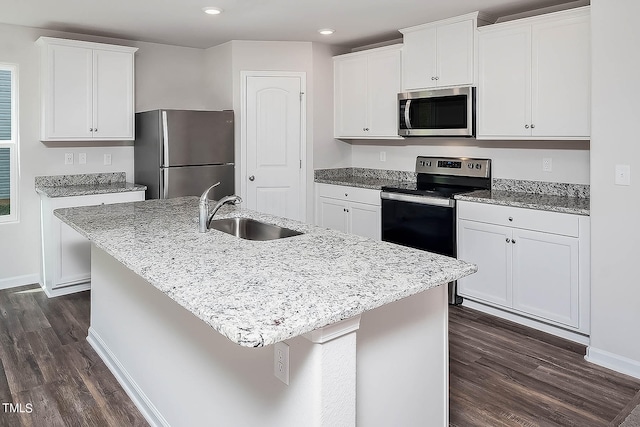 kitchen with appliances with stainless steel finishes, a center island with sink, white cabinetry, and sink