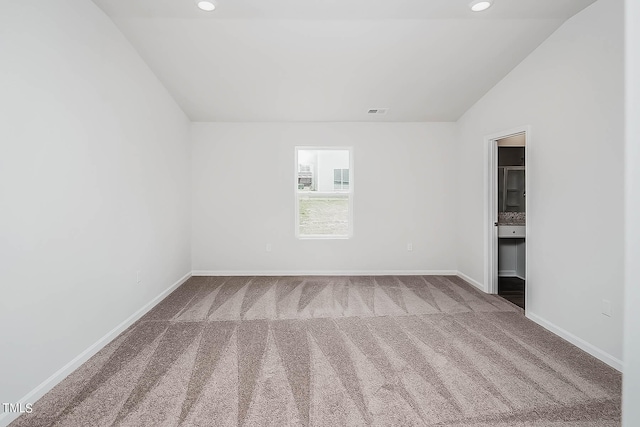 spare room featuring carpet floors and vaulted ceiling