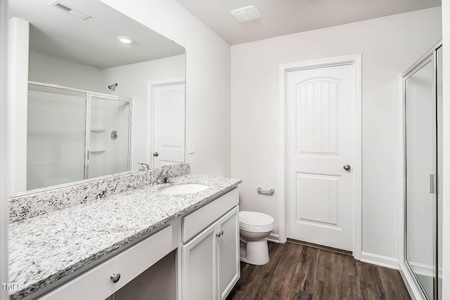 bathroom with hardwood / wood-style flooring, vanity, toilet, and walk in shower