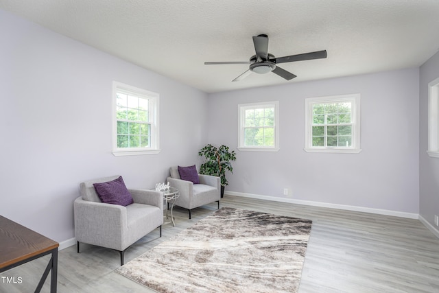 living area featuring hardwood / wood-style floors, ceiling fan, and a textured ceiling