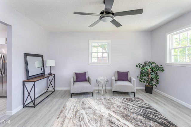 living area with ceiling fan and light wood-type flooring