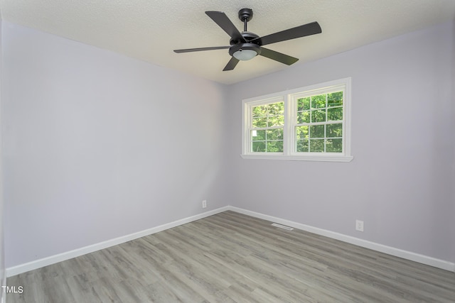 spare room with ceiling fan, light wood-type flooring, and a textured ceiling