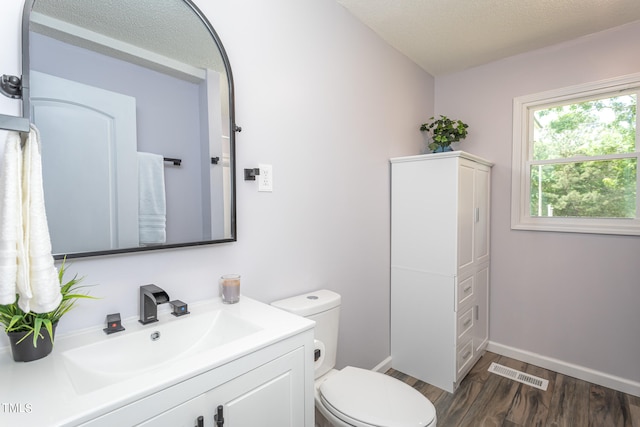 bathroom featuring toilet, vanity, and hardwood / wood-style floors