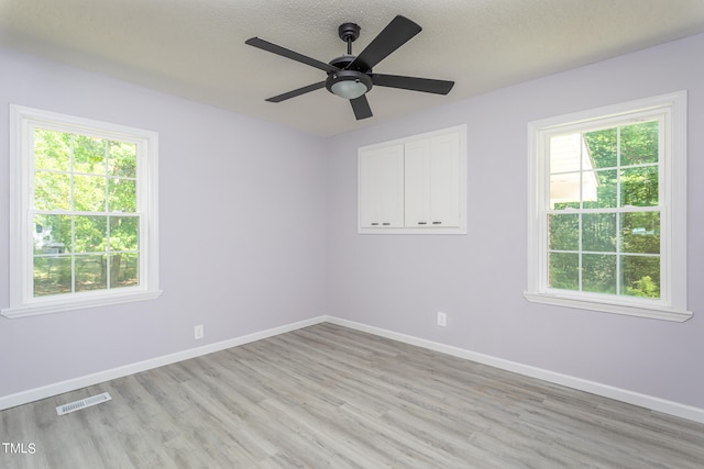 spare room with plenty of natural light, light hardwood / wood-style floors, and ceiling fan