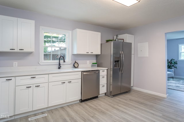 kitchen with light hardwood / wood-style flooring, stainless steel appliances, white cabinetry, and sink