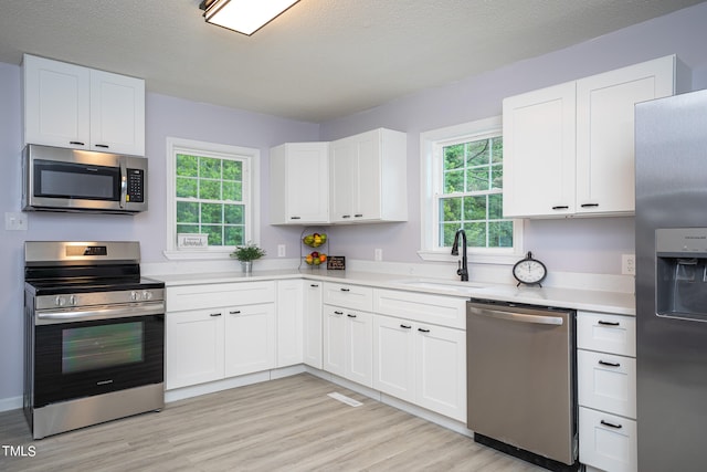 kitchen featuring light hardwood / wood-style floors, stainless steel appliances, white cabinetry, and sink