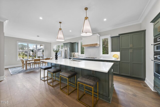 kitchen featuring appliances with stainless steel finishes, a large island with sink, plenty of natural light, and decorative light fixtures