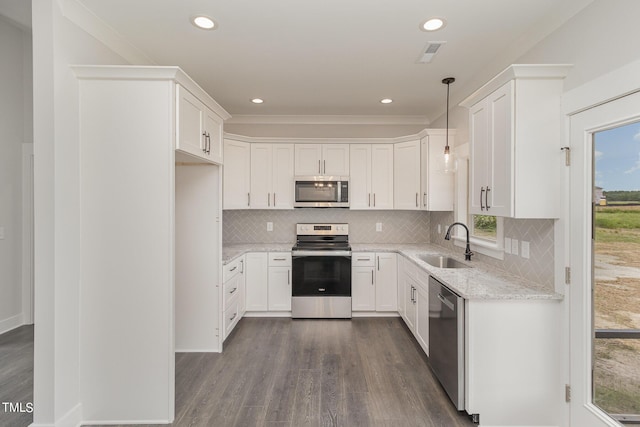 kitchen with hanging light fixtures, white cabinetry, appliances with stainless steel finishes, and a sink