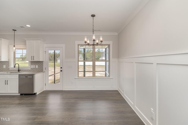 unfurnished dining area featuring an inviting chandelier, crown molding, dark wood-type flooring, and a sink