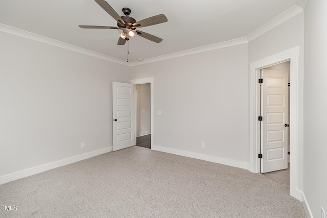 spare room with baseboards, ornamental molding, ceiling fan, and light colored carpet