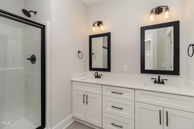 bathroom with double vanity, a stall shower, baseboards, and a sink