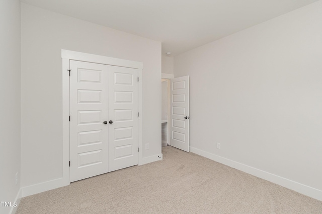 unfurnished bedroom with baseboards, a closet, and light colored carpet