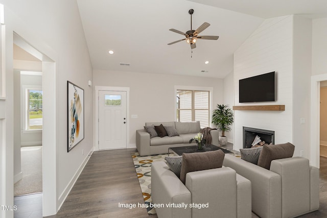 living area featuring a healthy amount of sunlight, a large fireplace, visible vents, and dark wood-type flooring