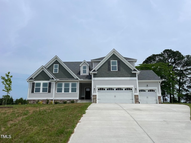 craftsman inspired home with a garage and a front lawn